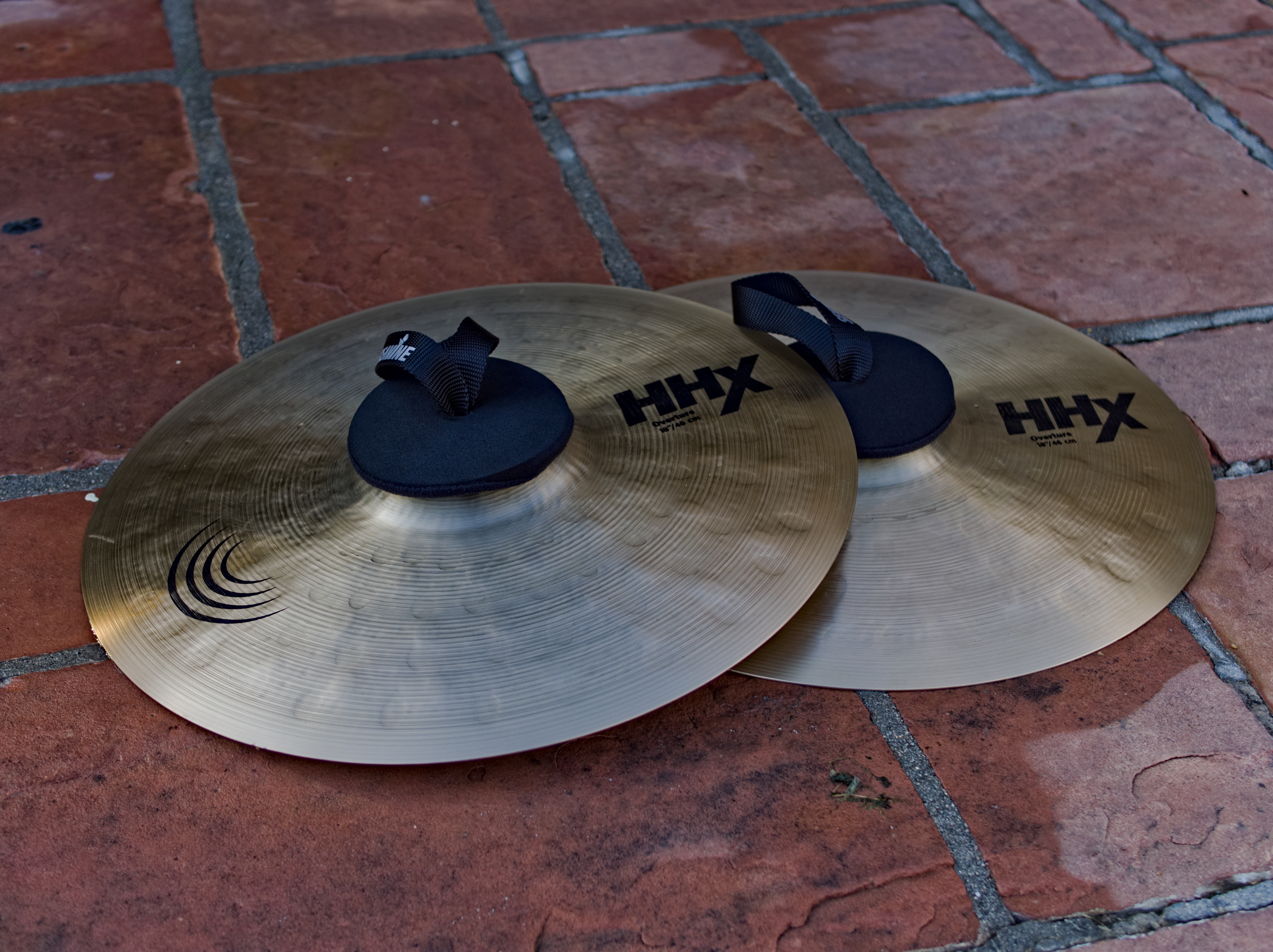 A pair of cymbals on brick